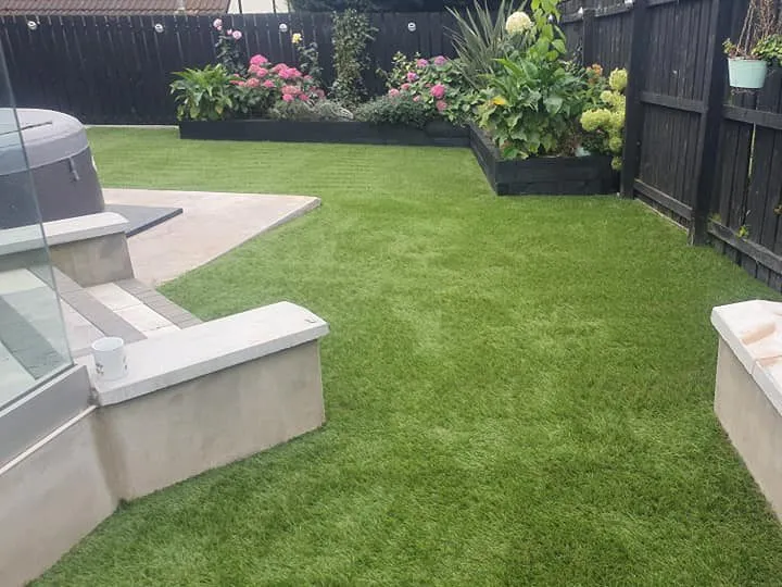 Garden with artificial grass and black wooden fence with matching planter