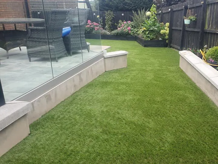 Garden with artificial grass and black wooden fence with matching planter