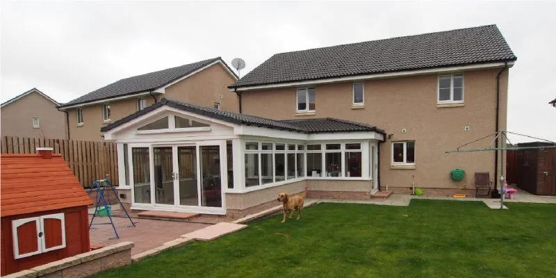 L shaped extension at the back of the house with dog running around the garden