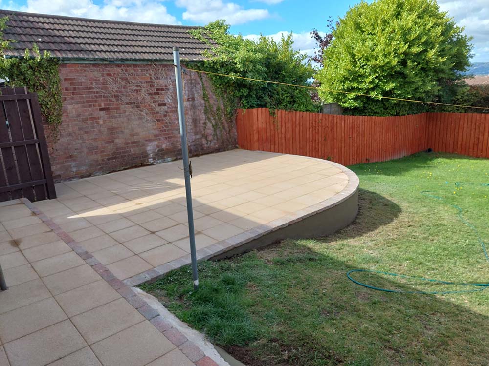 Newly laid raised patio with sandstone paving slabs and decoative border